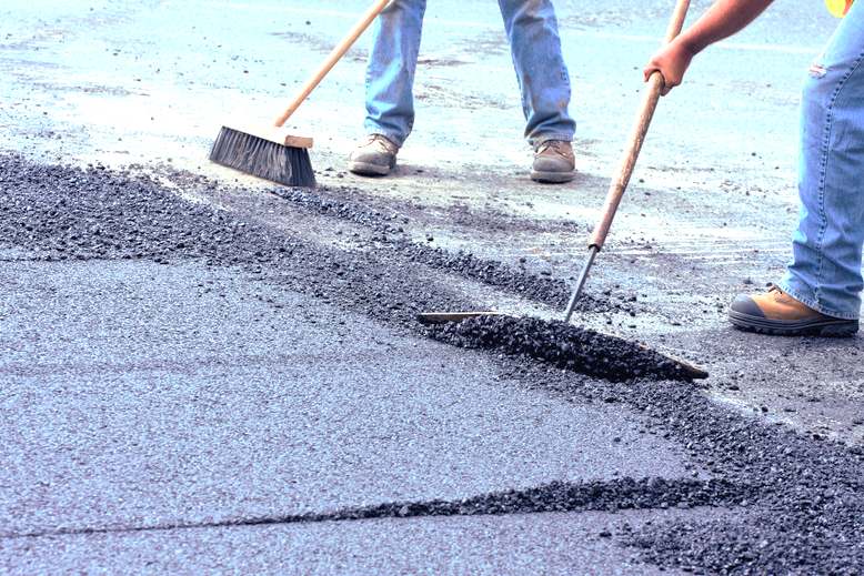Road construction crew laying and levelling asphalt